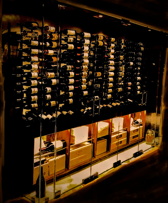wine bottles on metal racks in a glass enclosure