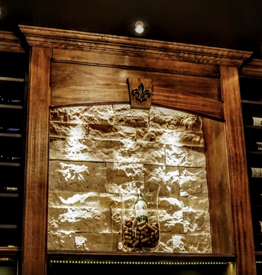 Traditional custom wine cellar by Baroque Design with rich wood cabinetry and stone wall accents.