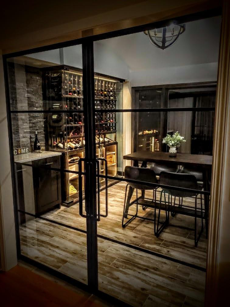a custom wine cellar beside a dining table, holding multiple bottles