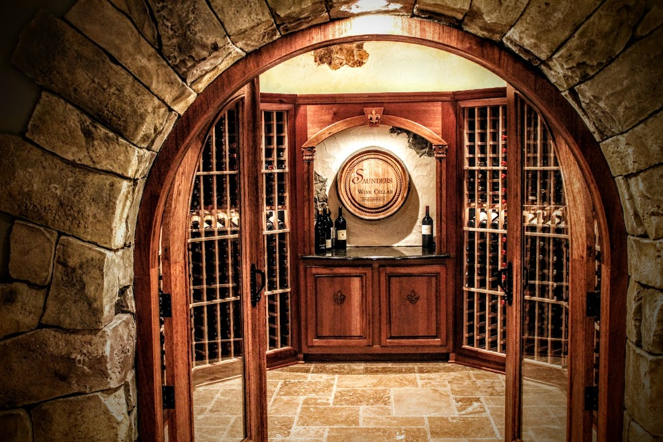 A cozy stone-arched wine cellar with wooden racks and cabinets filled with neatly stored wine bottles