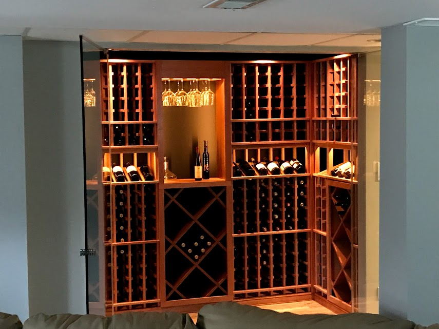 An elegantly built-in wooden wine cellar with illuminated racks and neatly arranged bottles behind glass doors
